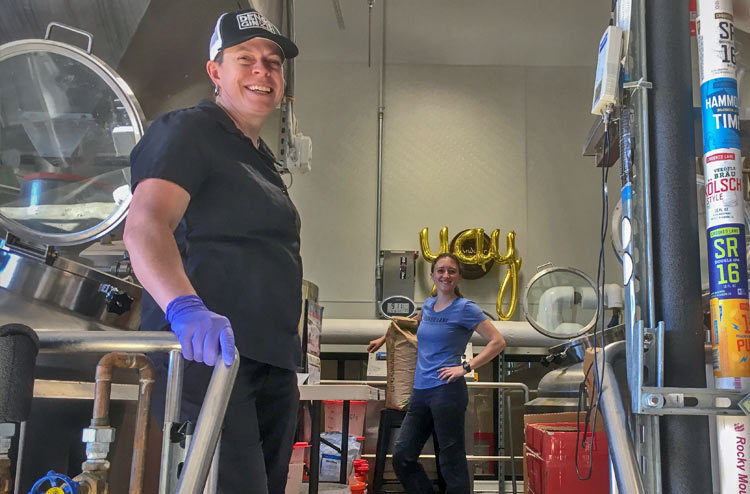 Brewery workers in a production facility with brewing equipment and balloons