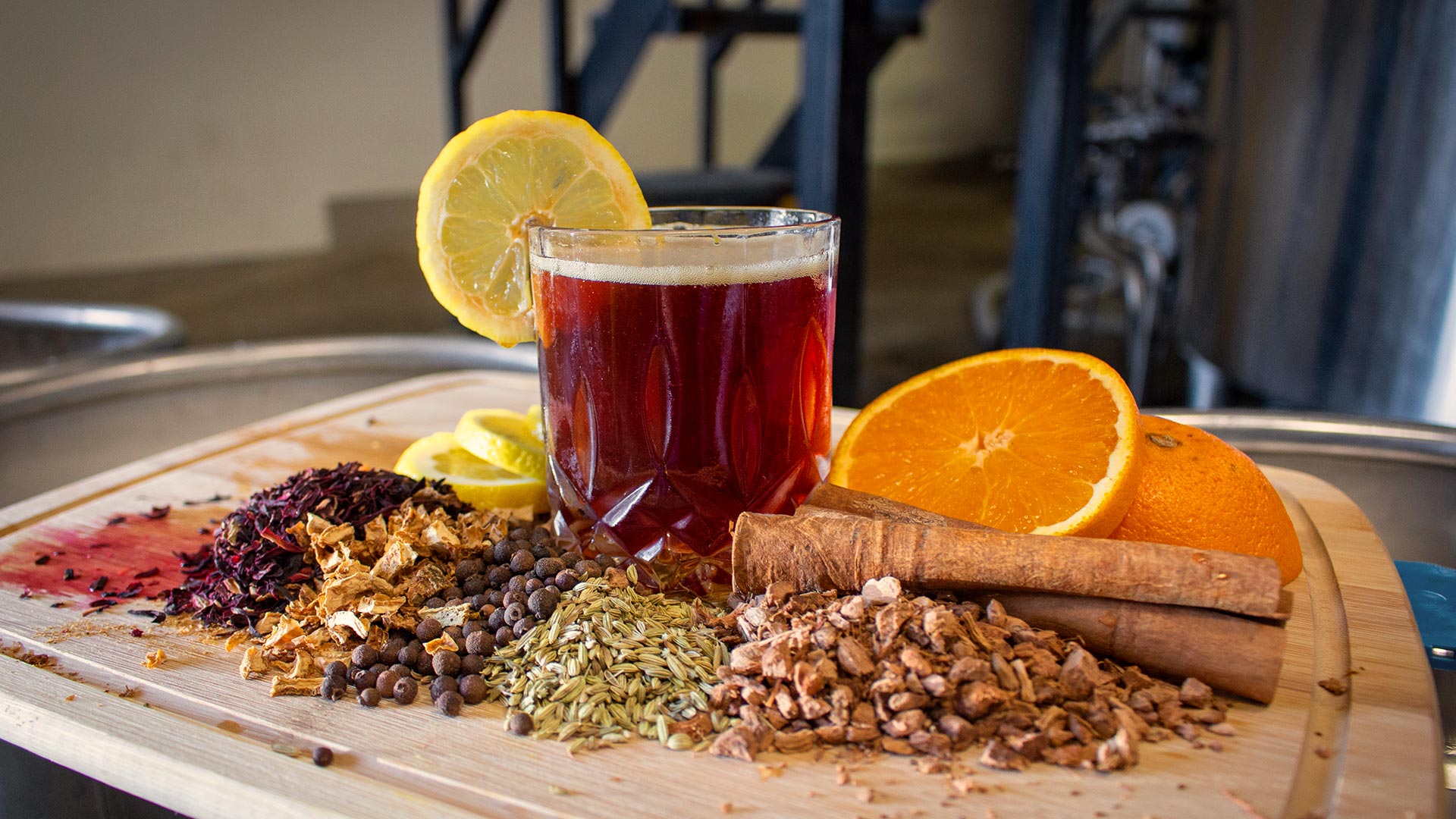 Spices, citrus, and a glass of mulled wine on a wooden board
