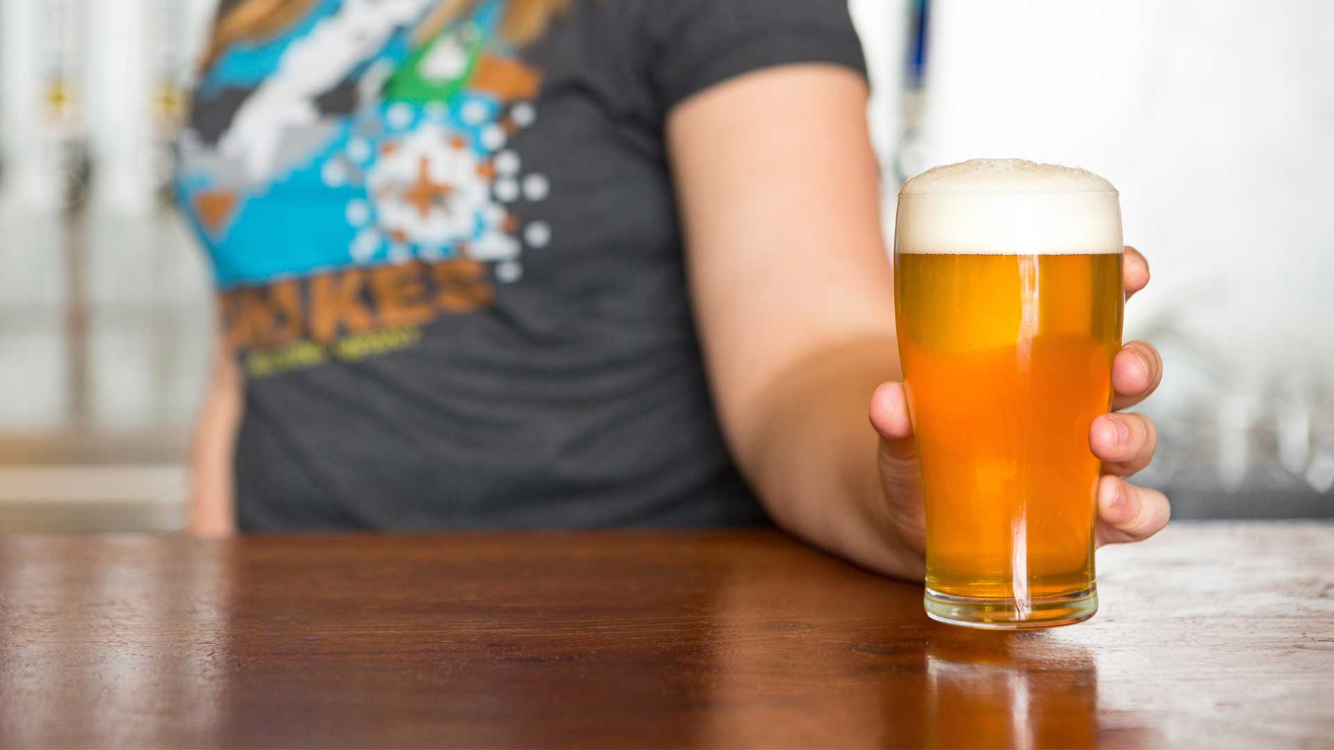 A women placing a glass of beer on the bar