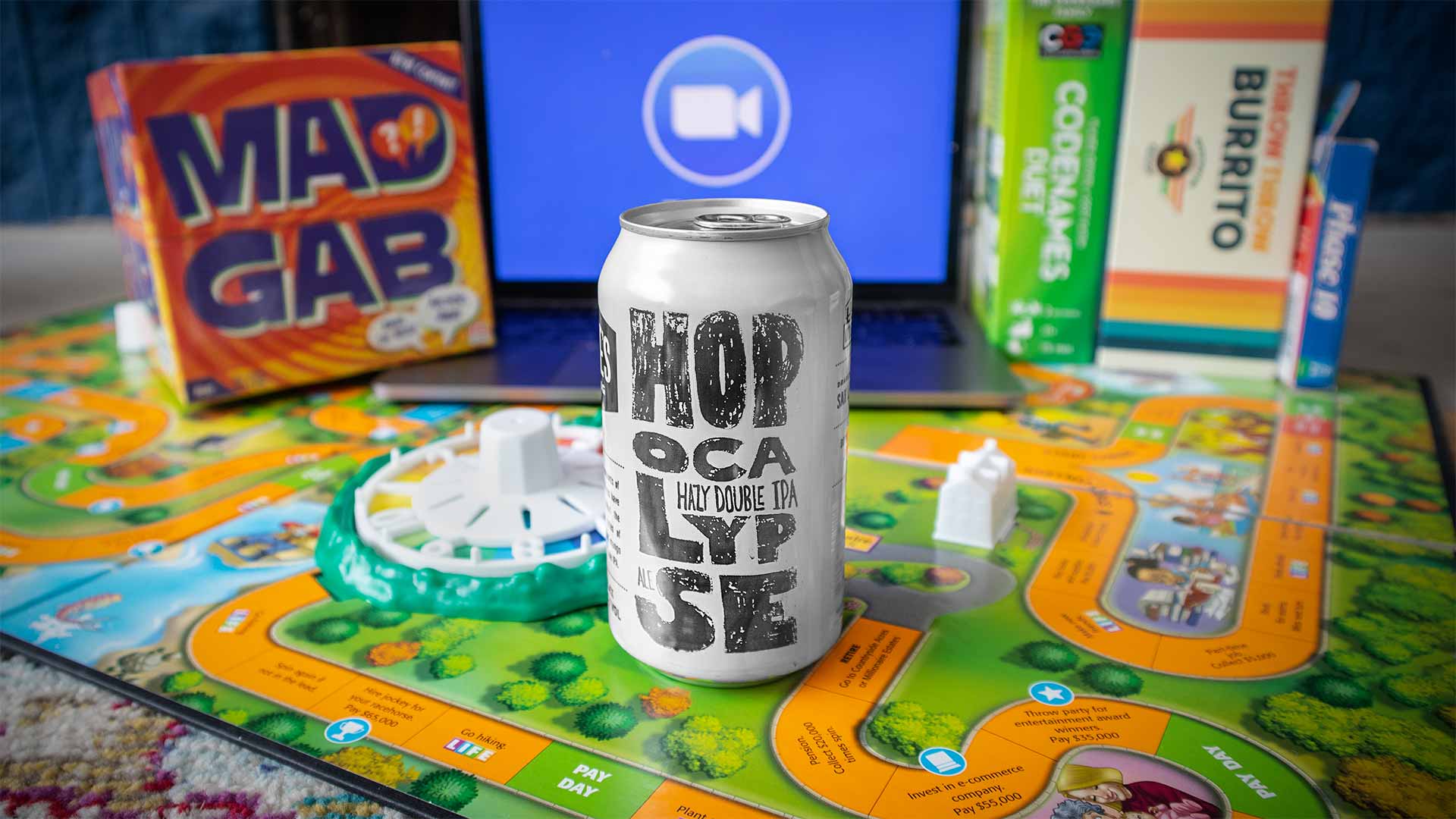 Game night setup: The Game of Life, Mad Gab, Codenames, and a can of Hopocalypse beer