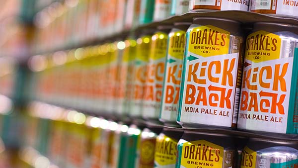 Empty cans of Kick Back IPA stacked on a pallet for canning