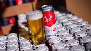 Can of Cold IPA with pint glass sitting on full cases of beer