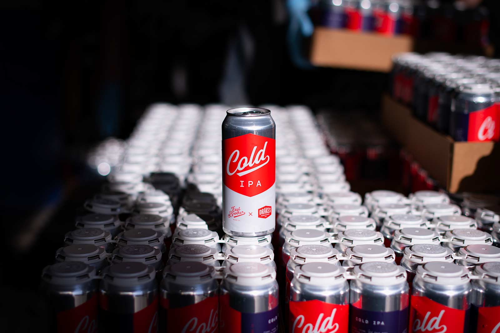 Cold IPA cans lined up, one prominent can in focus with red and gray branding