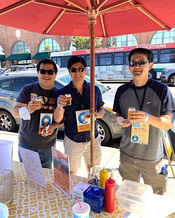 Three men in sunglasses holding beers at an outdoor event