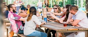 Friends enjoying drinks and conversation at an outdoor picnic table