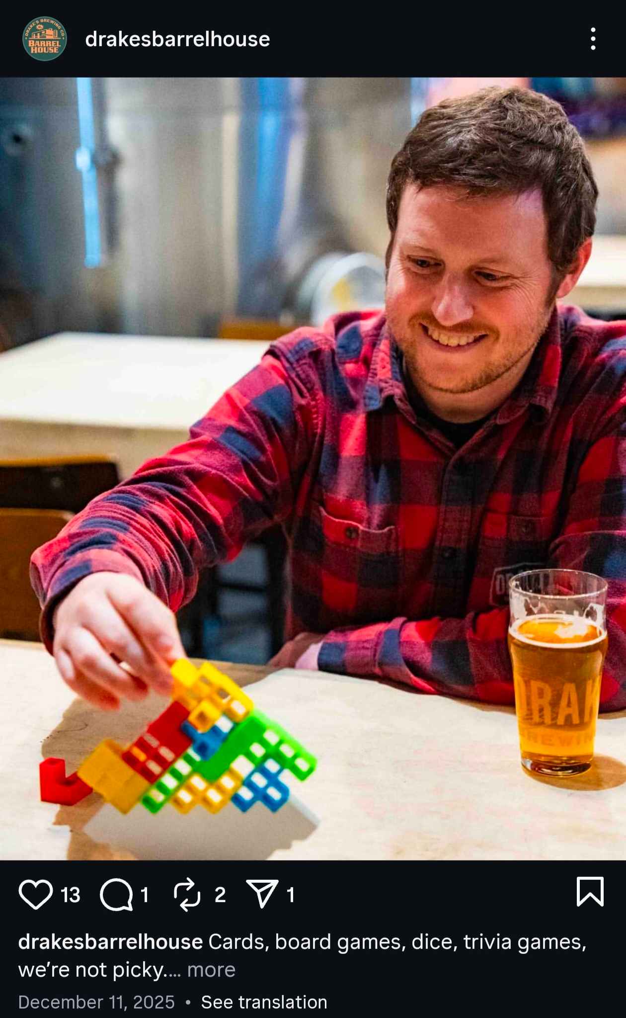Man playing a colorful board game at Drakes Barrel House with a beer