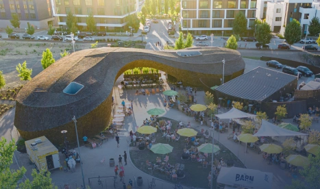 Outdoor event with people dining under a unique arched structure with yellow umbrellas
