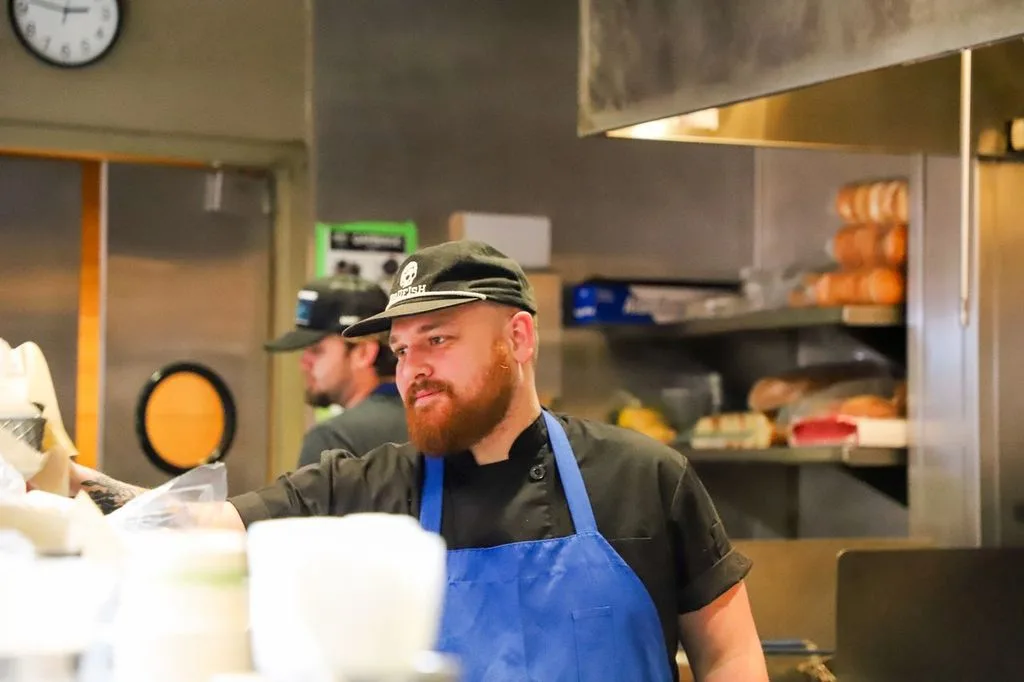Chef with red beard in blue apron working in kitchen