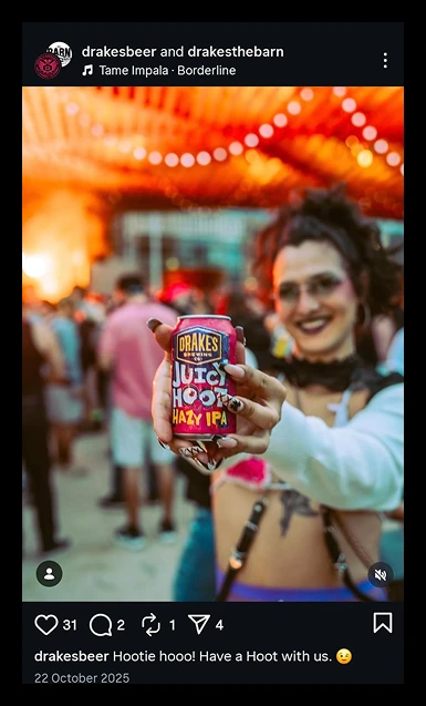 Drake's Brewing Co. Juicy Hoot Hazy IPA can held by a smiling person with festive lights