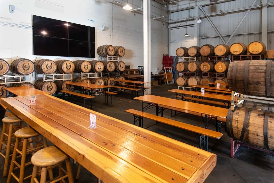 Wooden tables and benches in a distillery tasting room with barrels