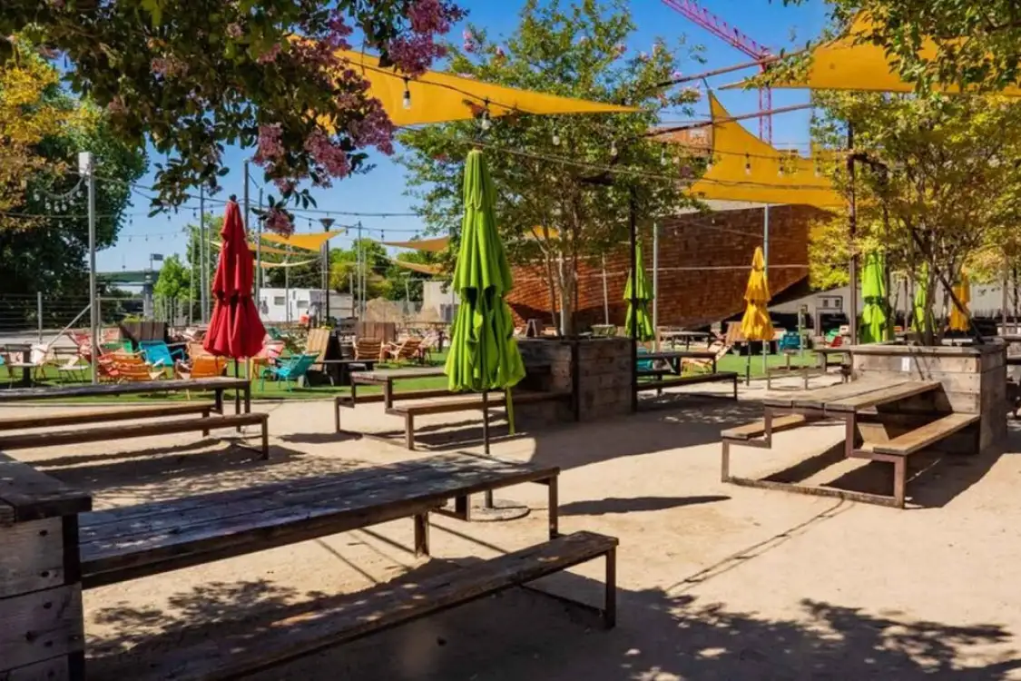 Outdoor beer garden with picnic tables, umbrellas, and string lights