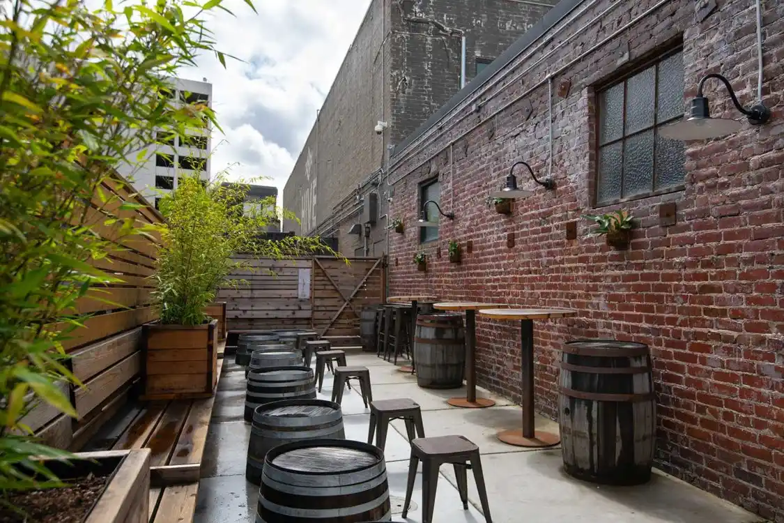 Rooftop bar seating with whiskey barrels, wooden deck, and brick wall
